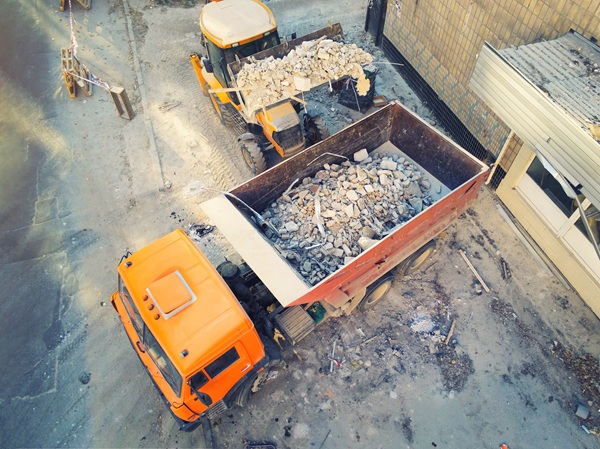 A bulldozer uploading waste and debris into dump truck at construction site in New York City.